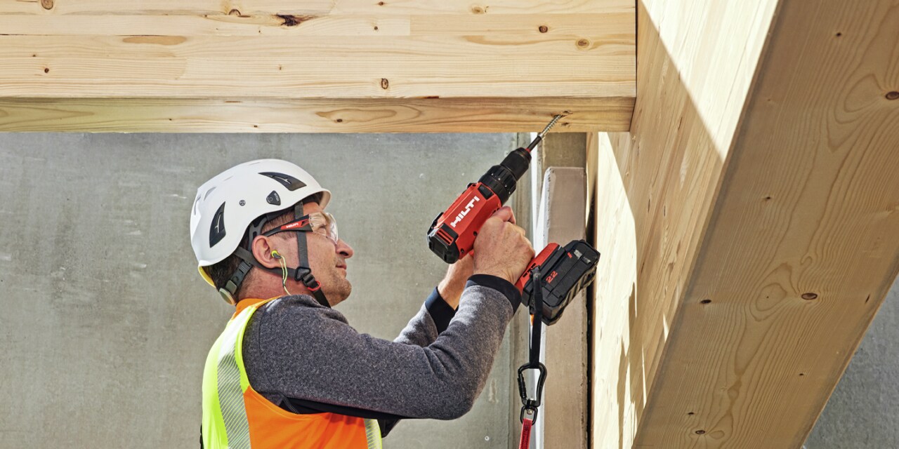 Worker installs a wooden beam. 