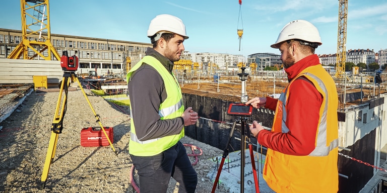 Arbeiter auf der Baustelle mit Hilti Totalstation und Tablet