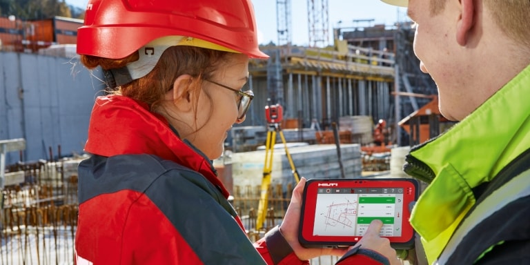 Arbeiter mit Hilti Tablet und Totalstation auf der Baustelle