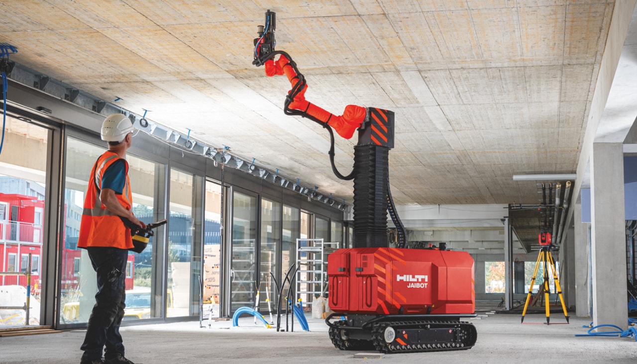 Bauarbeiter bei der sicheren Bedienung des Bohrroboters Jaibot für Decken auf einer Baustelle