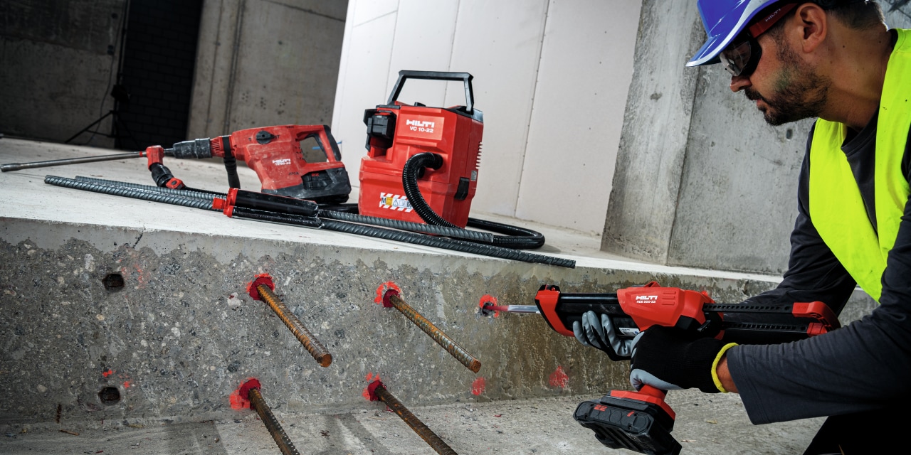Ein Mitarbeiter mit dem Nuron Akku-Auspressgerät HDE 500-22, Hilti Akku-Baustellensauger VC 10-22 und Nuron TE 60-22 Akku-Bohrhammer auf der Baustelle