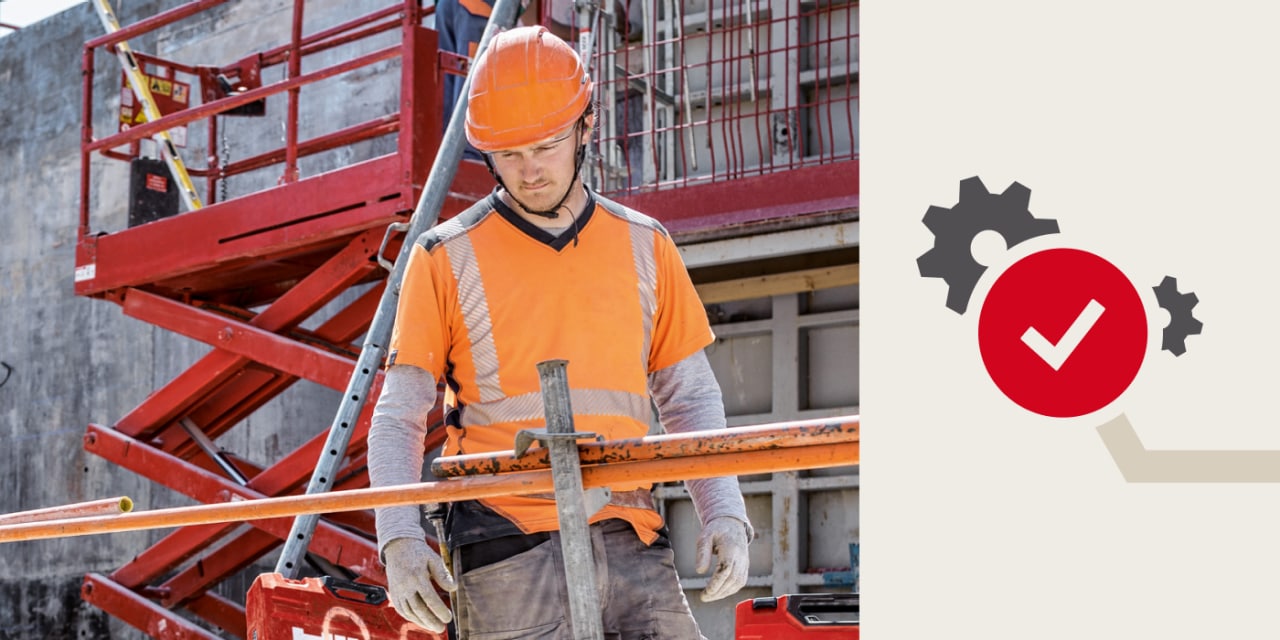 Ein Bauarbeiter in Sicherheitskleidung blickt von einem Gerüst auf der Baustelle hinab. 