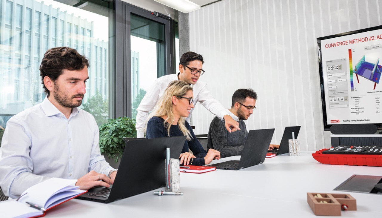 Personen sitzen in einem Büro vor ihrem Laptop.