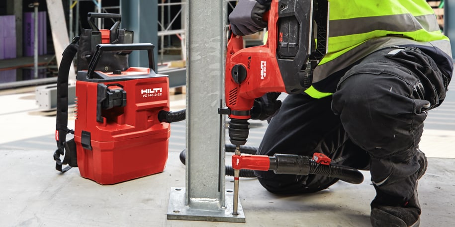 Arbeiter bohrt Grundplatte mit Hilti TE 30-22 Akku-Bohrhammer und VC 10-22