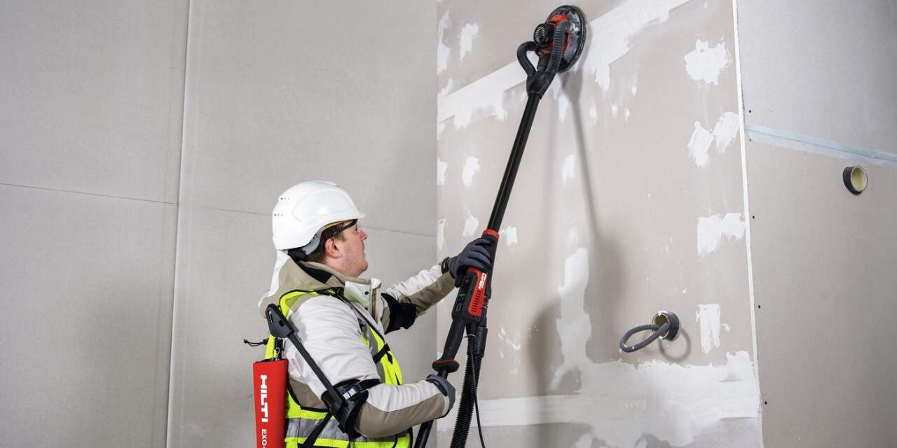 Ein Arbeiter arbeitet mit dem Hilti DWS 225 Langhalsschleifer auf einer Trockenbaustelle