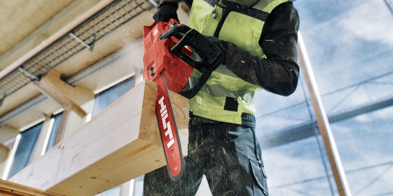 Arbeiter mit Hilti Akku-Kettensäge SCN 60-22 beim Sägen eines Holzbalkens