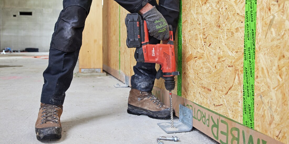 Arbeiter bohrt Loch mit Hilti Akku-Bohrhammer in Beton