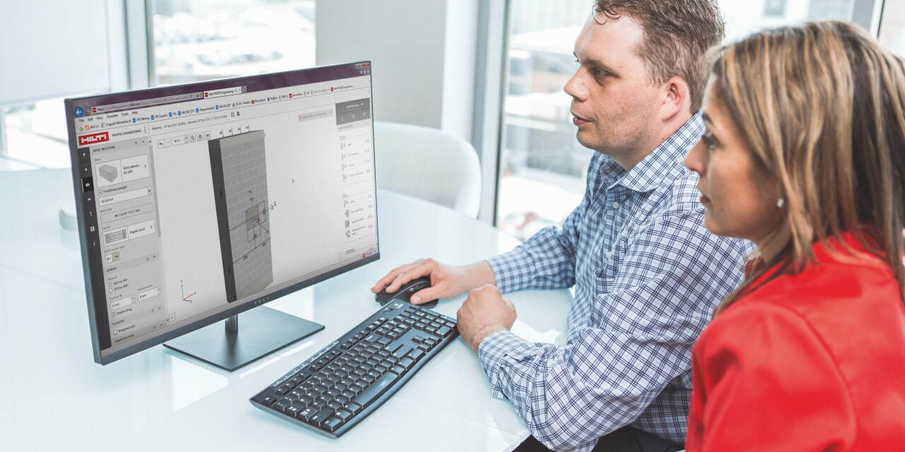 2 Personen an einem Schreibtisch vor einem Desktop-Bildschirm, der ein Ankerdesign anzeigt