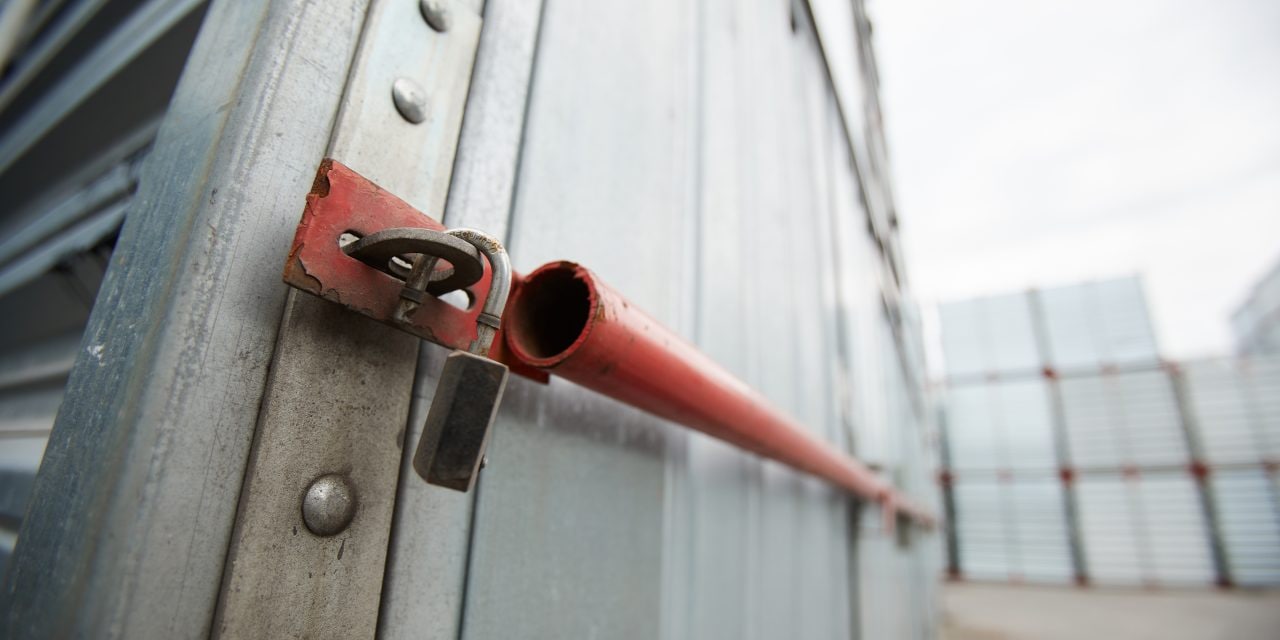 Close-up of sealed metal shipping container, hanging open lock after burglary