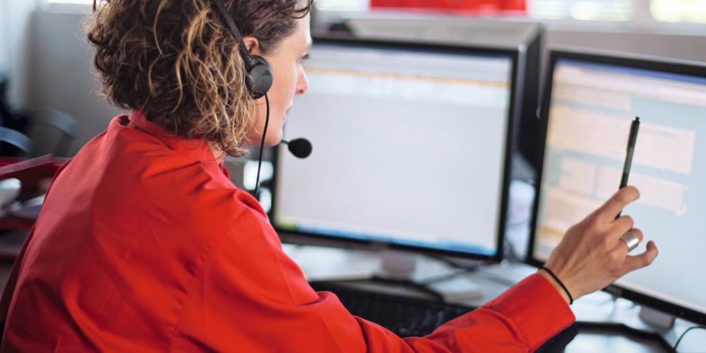 Frau im Kundenservice mit Headset am Bildschirm